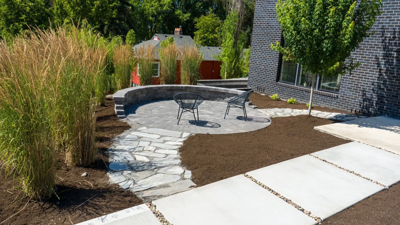 Round patio seating area surrounded by a cement walkway, decorative bark and tall grasses