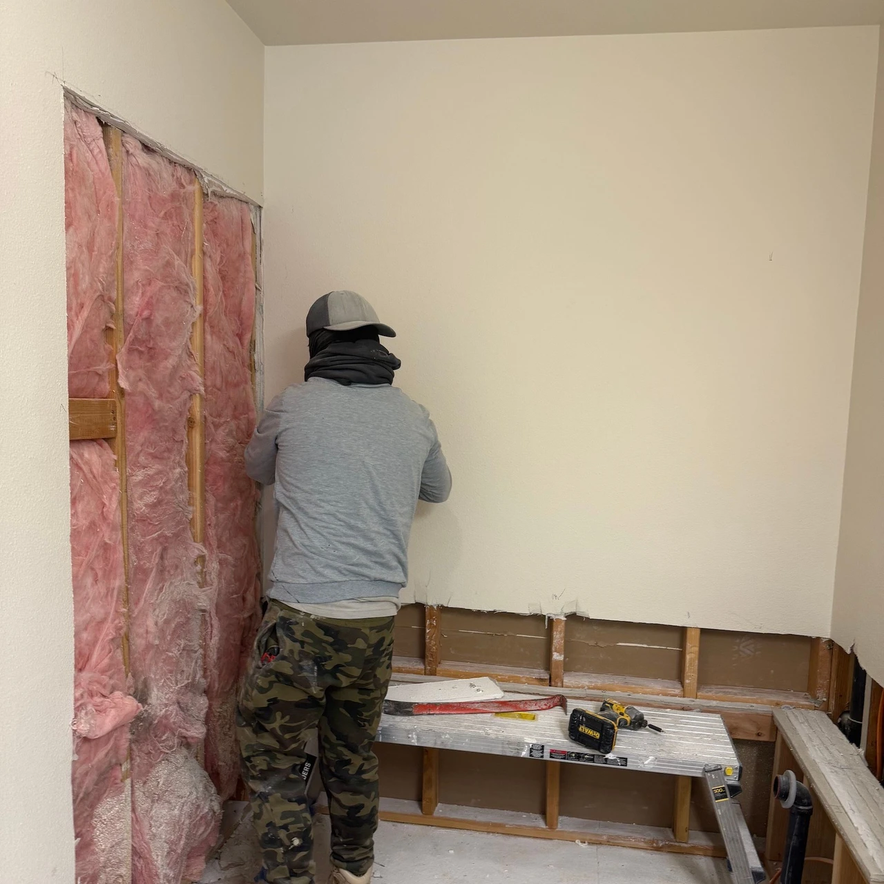 Worker replacing a drywall section for a shower installation