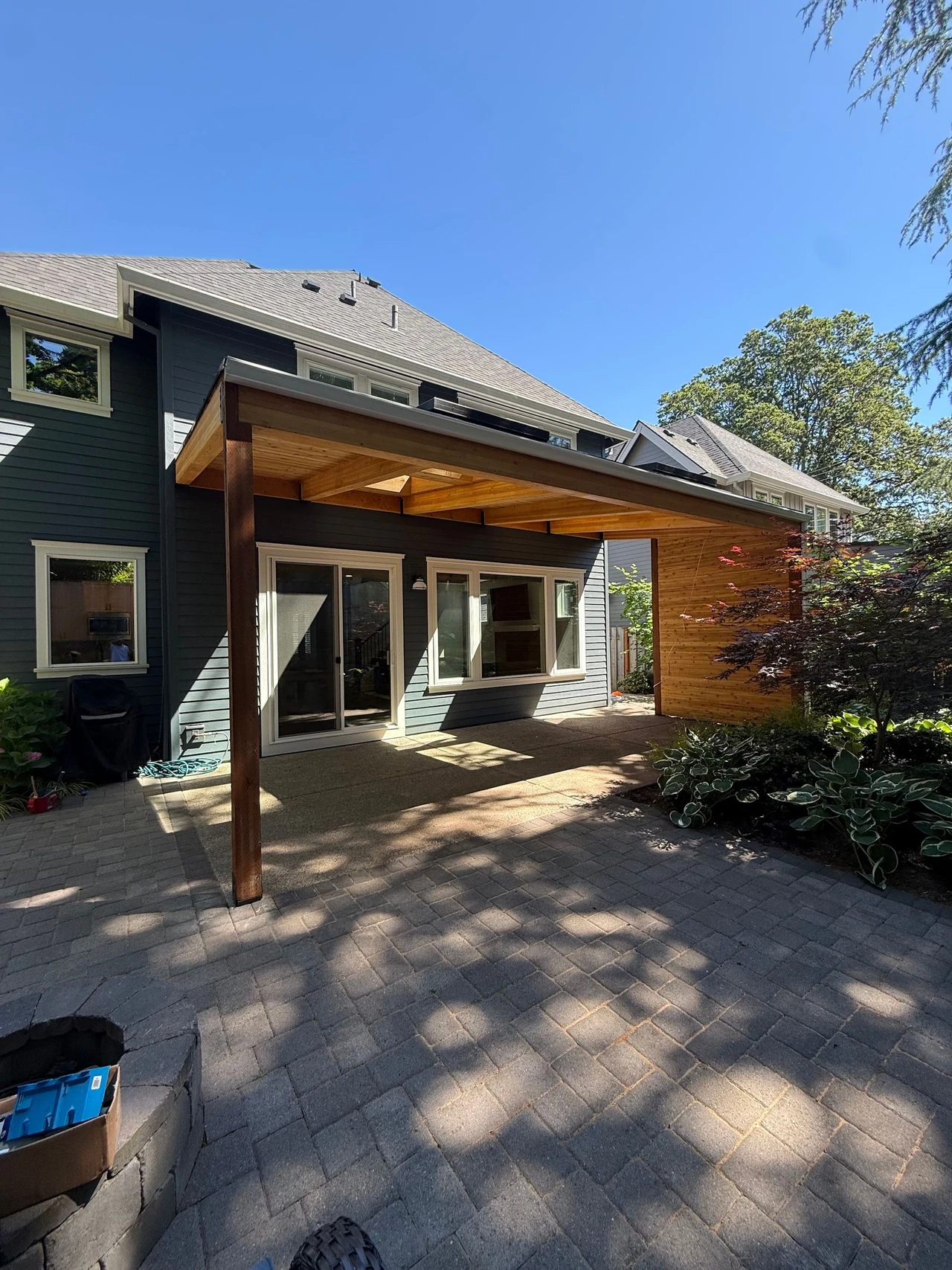patio cover on a blue house with bushes to the side