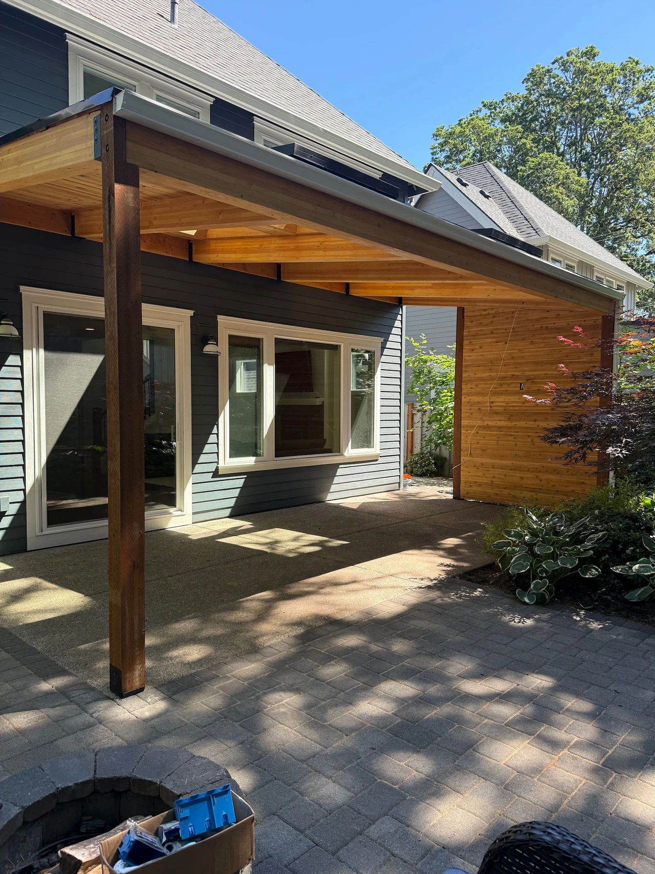 patio cover on a blue house with bushes to the side