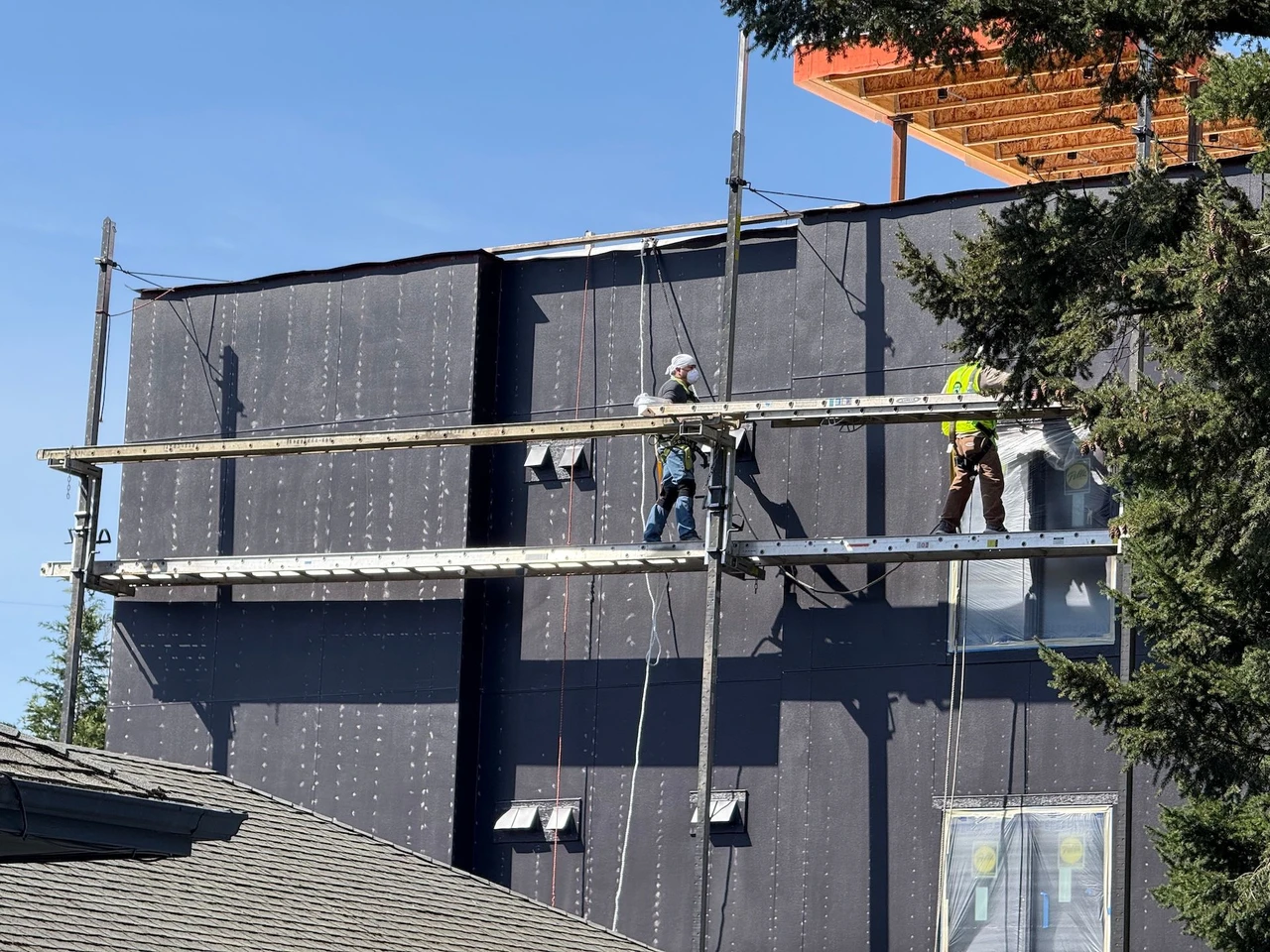 Workers painting the outside of a large grey building