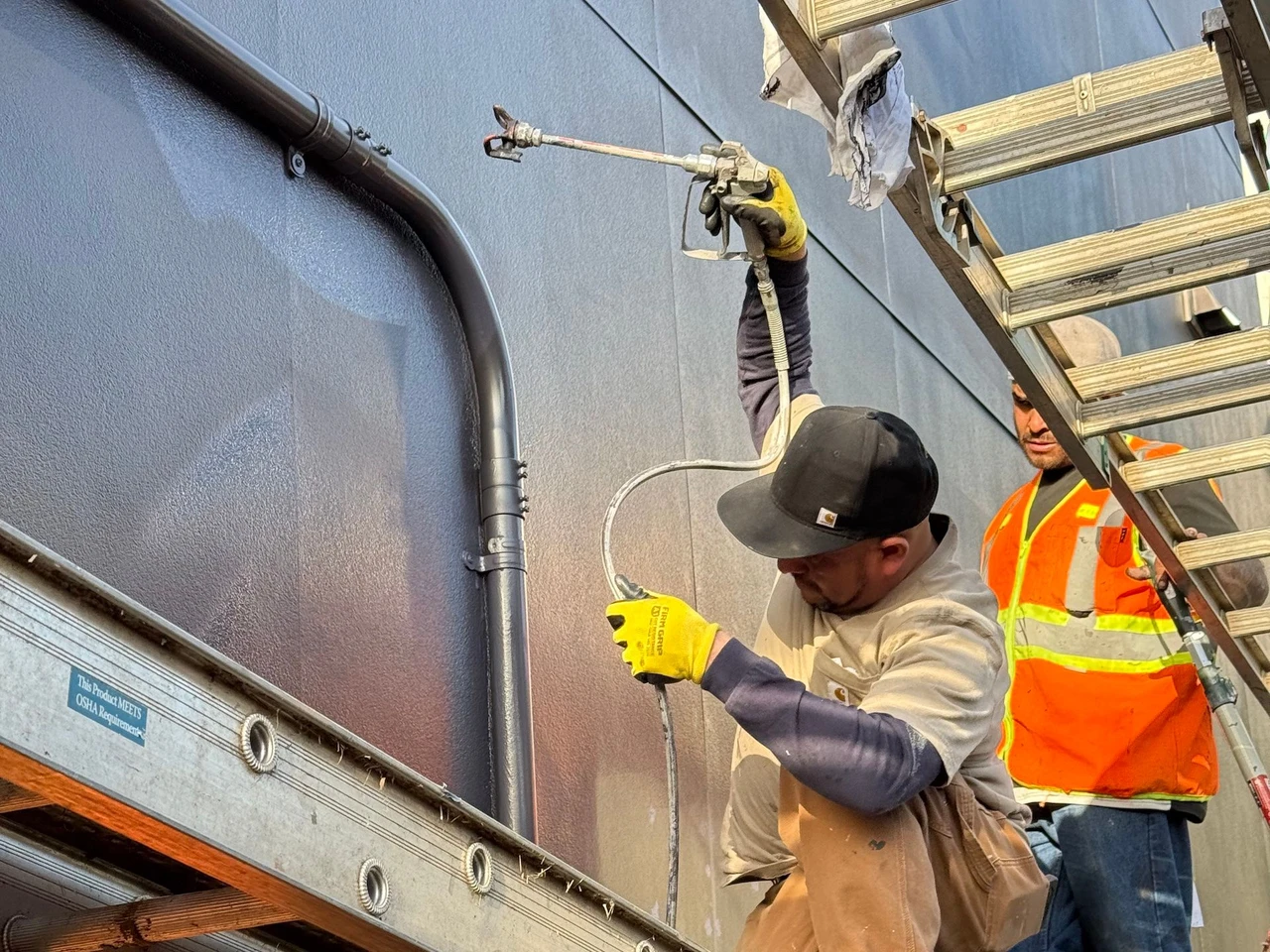 Worker painting a wall with a spray gun