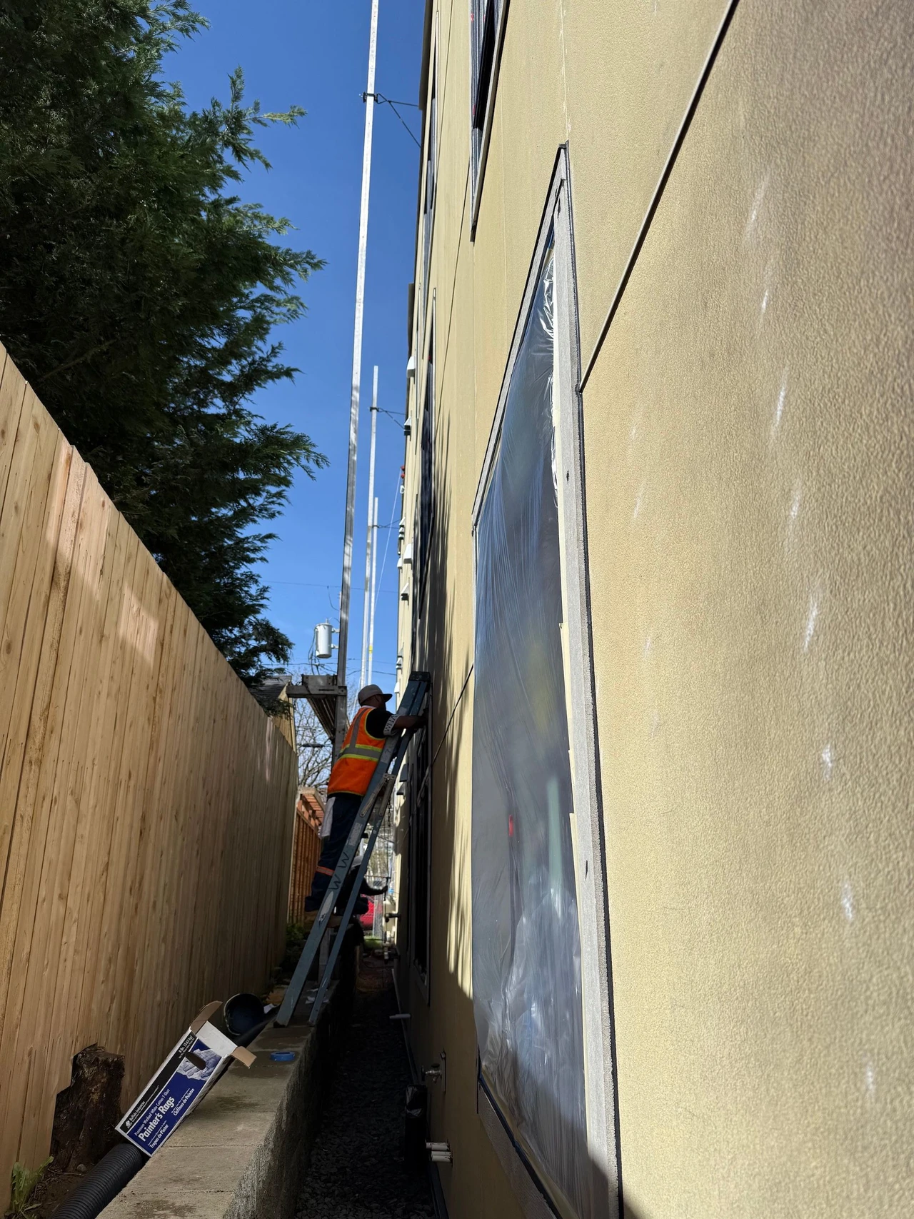 A worker on a ladder painting the side of a commercial building