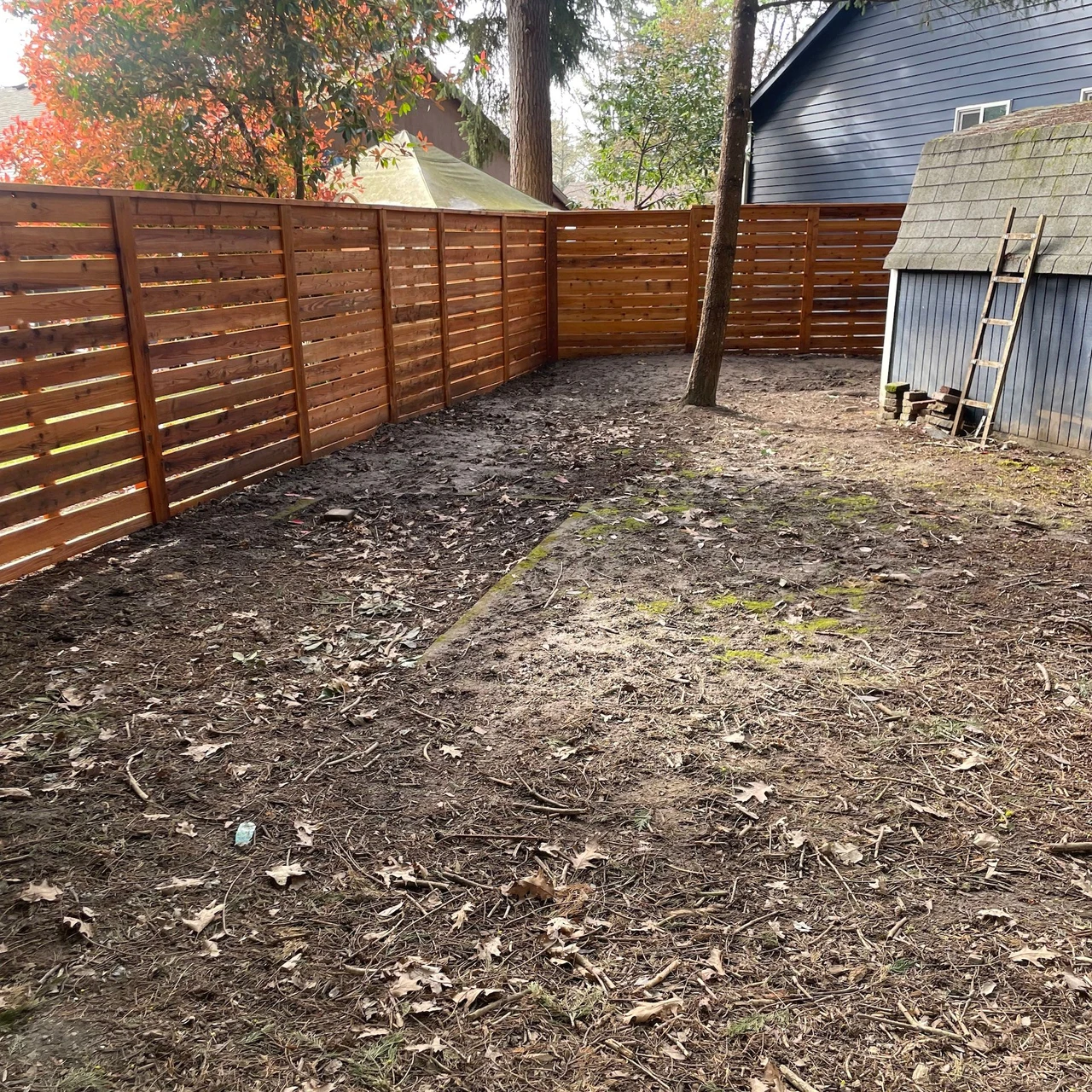 Slatted fence surrounding a dirt back yard