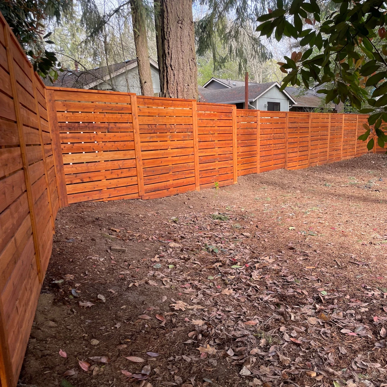 Corner of a bright colored fence around a dirt backyard