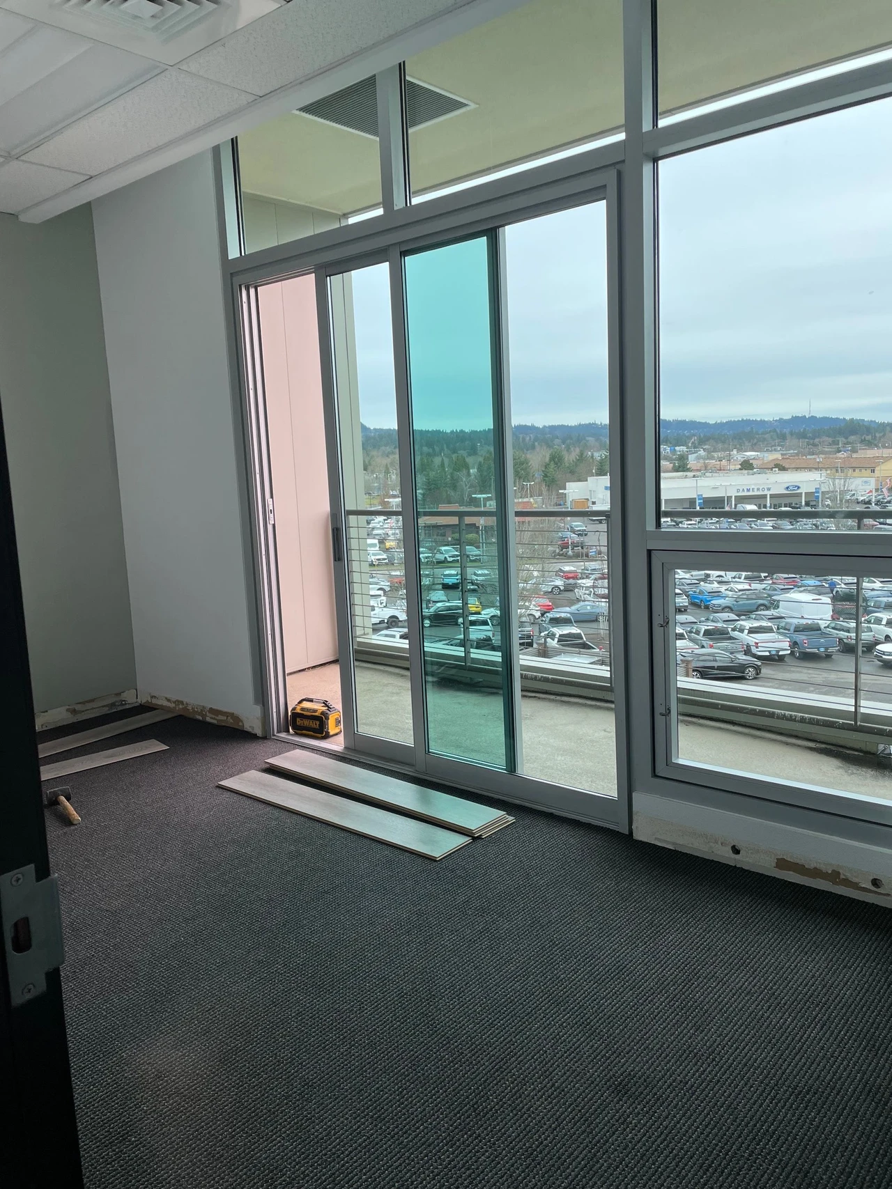 Old carpet inside of an office space with some laminate flooring pieces being sampled on top