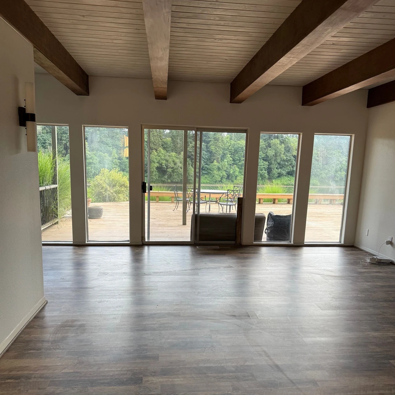 Room with floor to ceiling windows. Hardwood floors and ceiling with exposed trusses