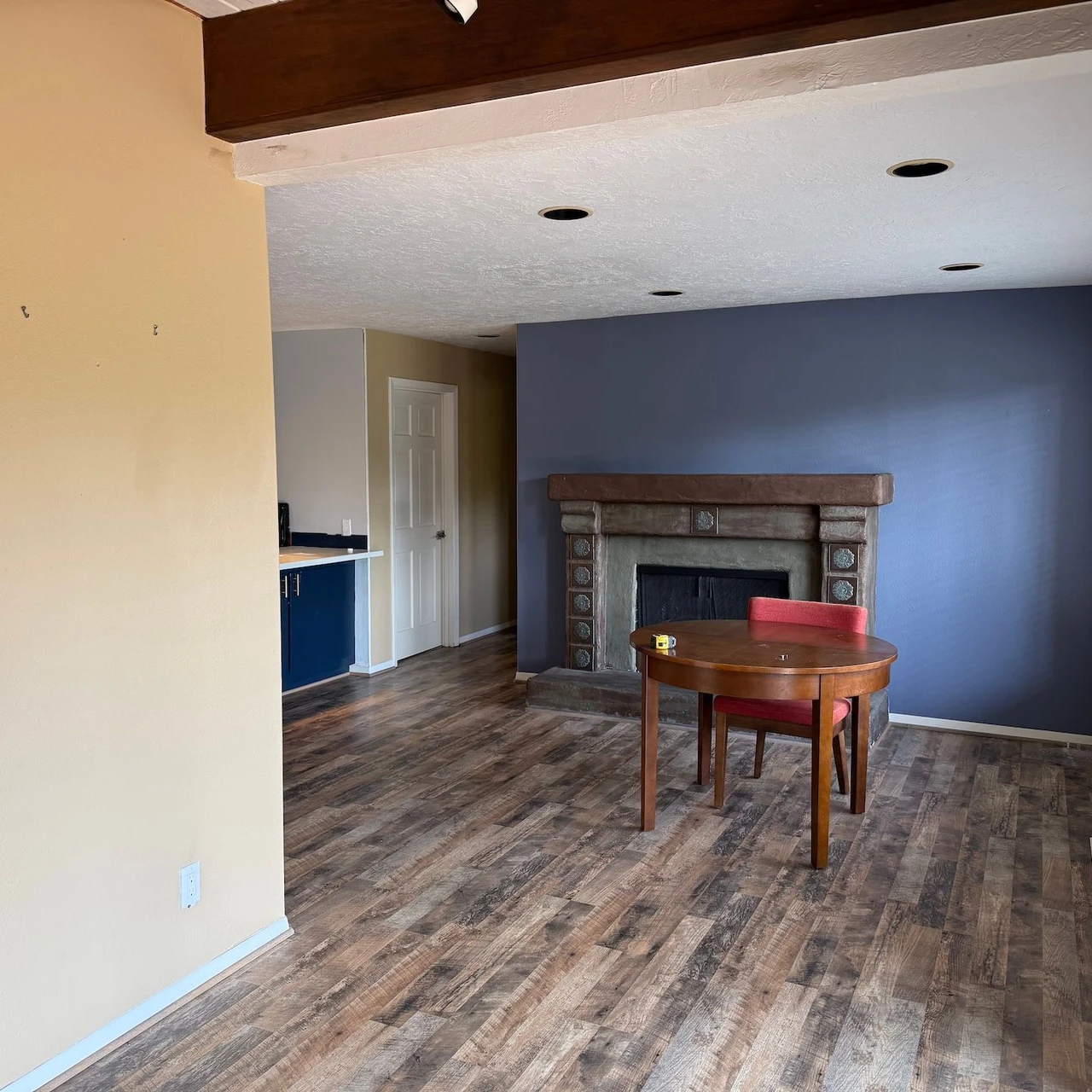 Room with a blue colored back wall, hardwood floors, and a table with a chair in the middle