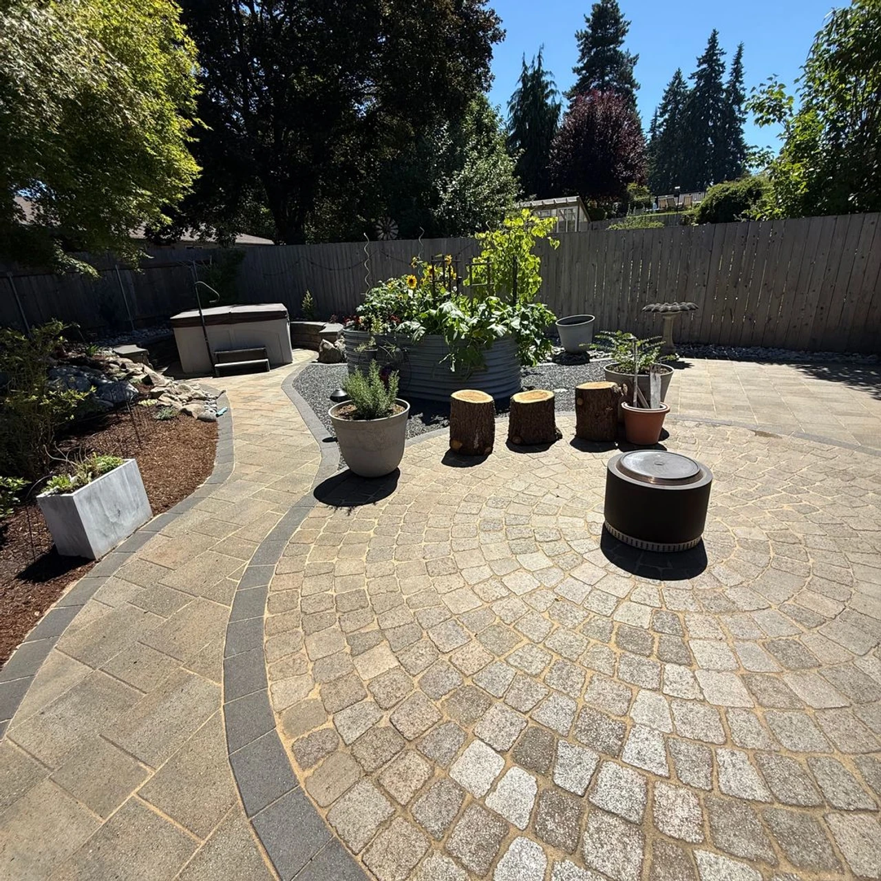 Pavers installed with a circular pattern in a backyard with many plants