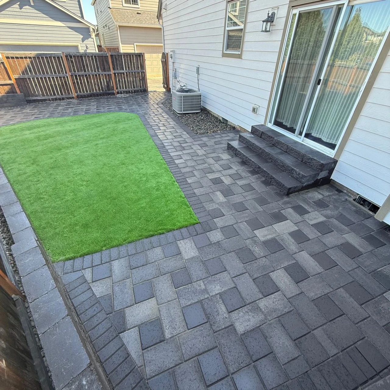 Backyard with multi shade pavers and a small turf yard