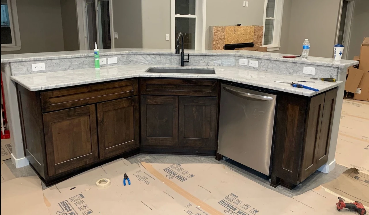Kitchen island with dark brown finishes, a sink and a dishwasher