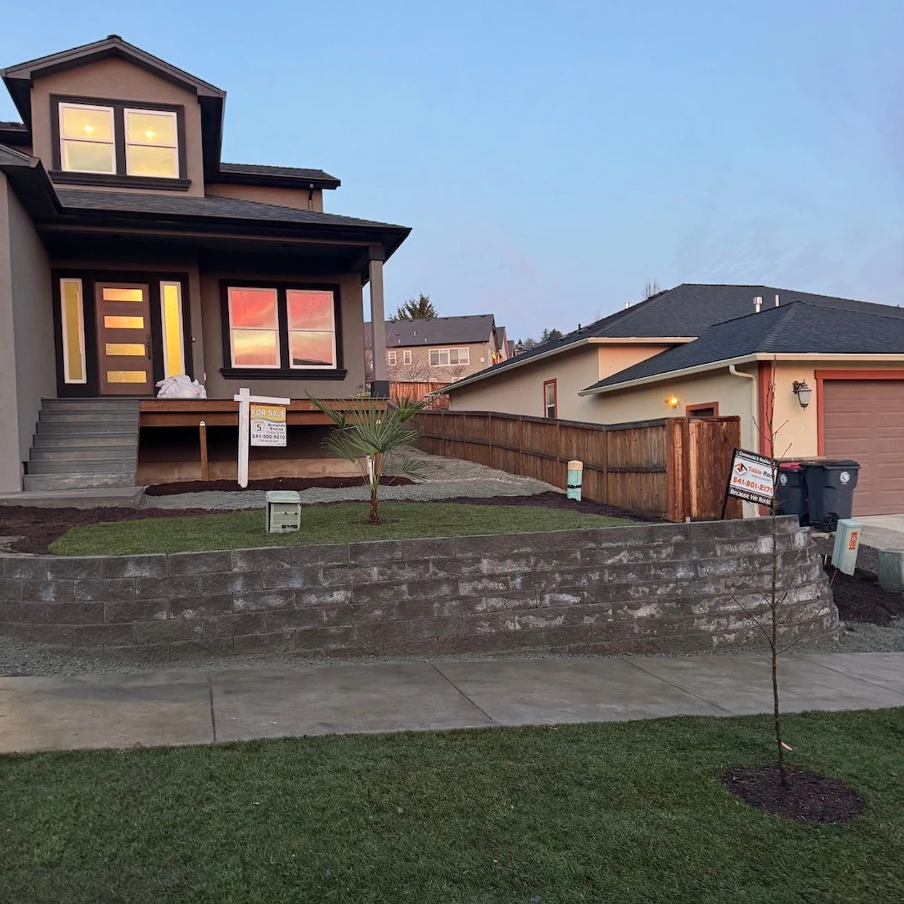 Brown house in the background with a terraced front yard and a sidewalk in front