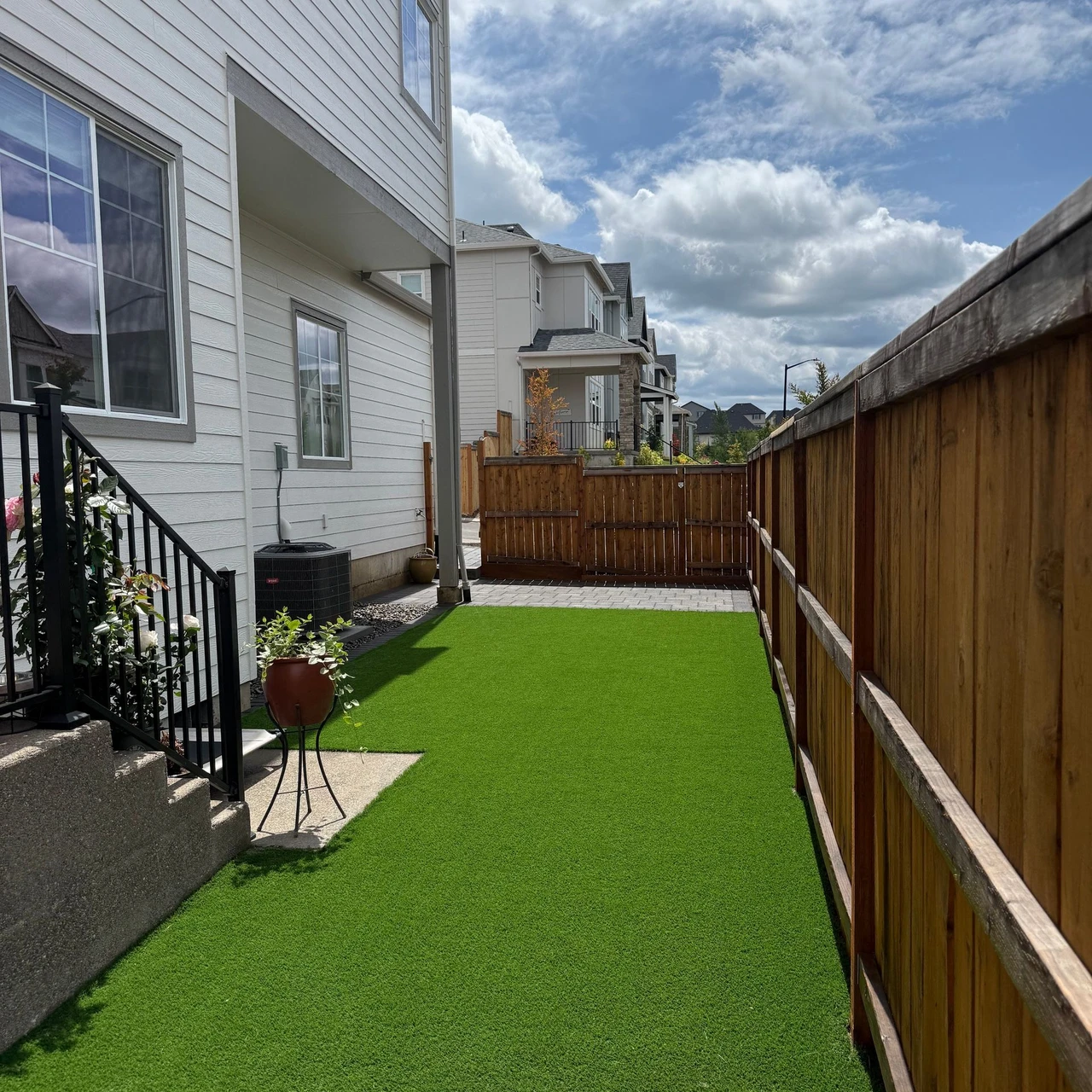 Staircase to the left, wooden fence the right. Green turf on the floor