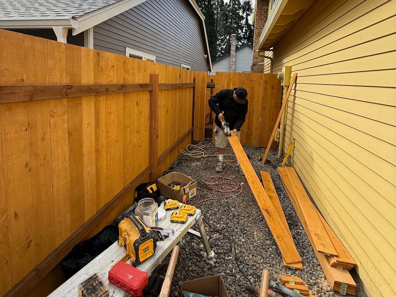 Worker cutting wood planks to add to a new fence