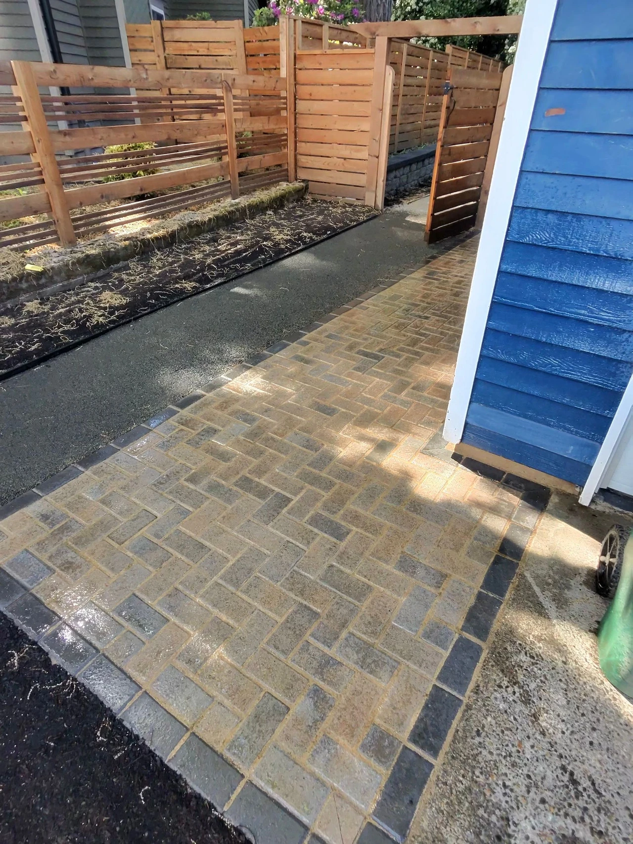 corner of a house with paver patio, custom fence and gravel walkway