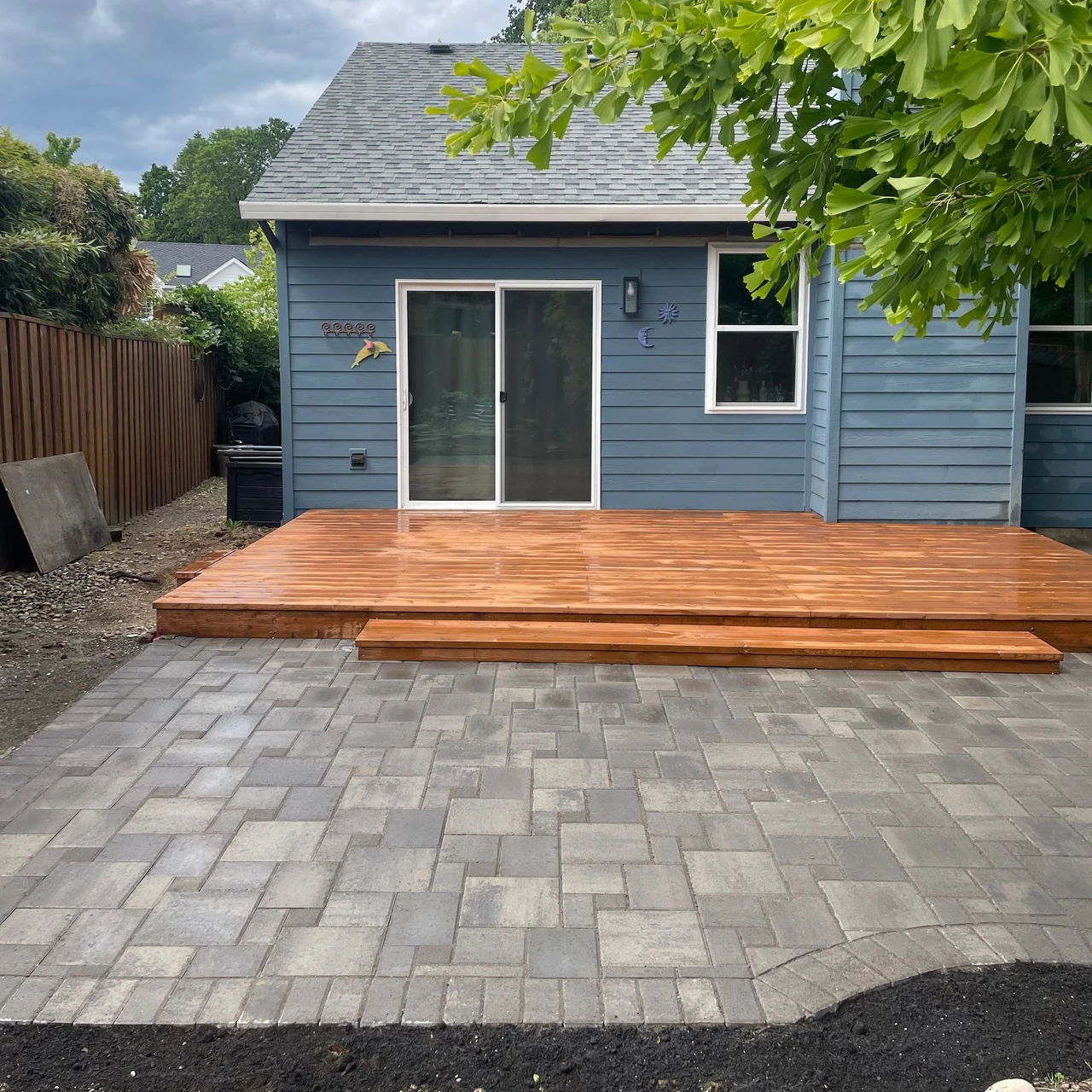 Blue house with a wooden deck and paver patio