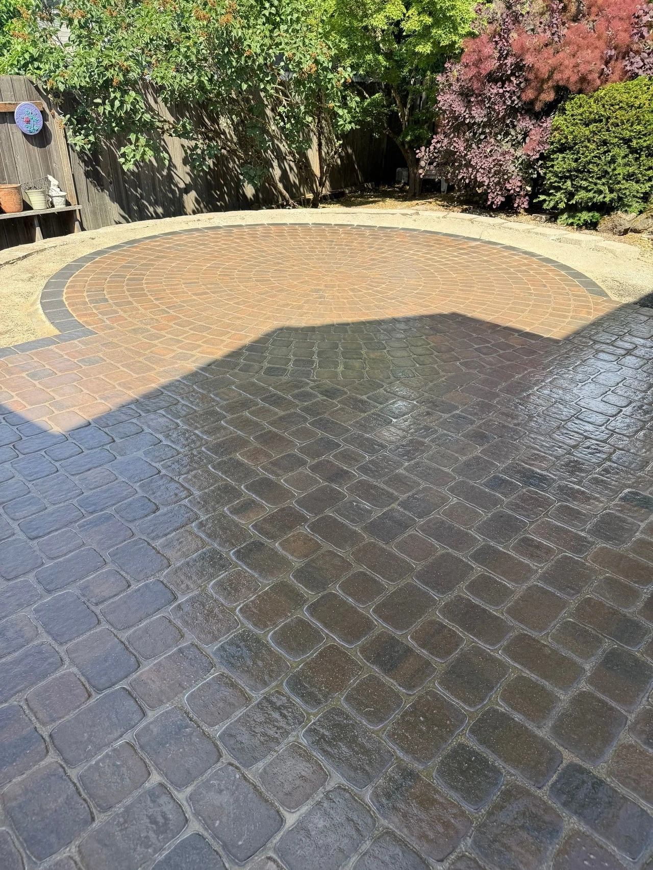 Paver patio with circular shape in the end and bushes in the background