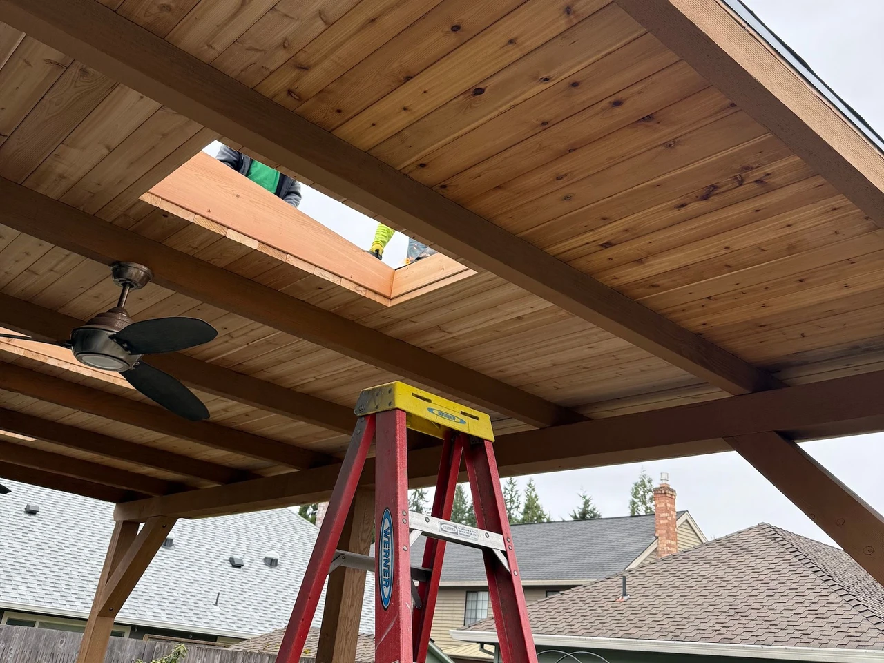Wooden roof being built over a porch with a ladder in the center