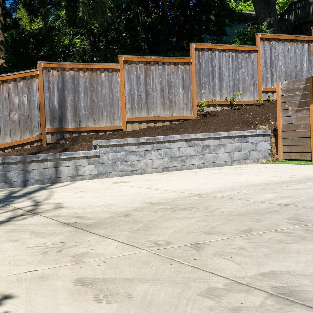 Small retaining wall along a hillside with a fence on top