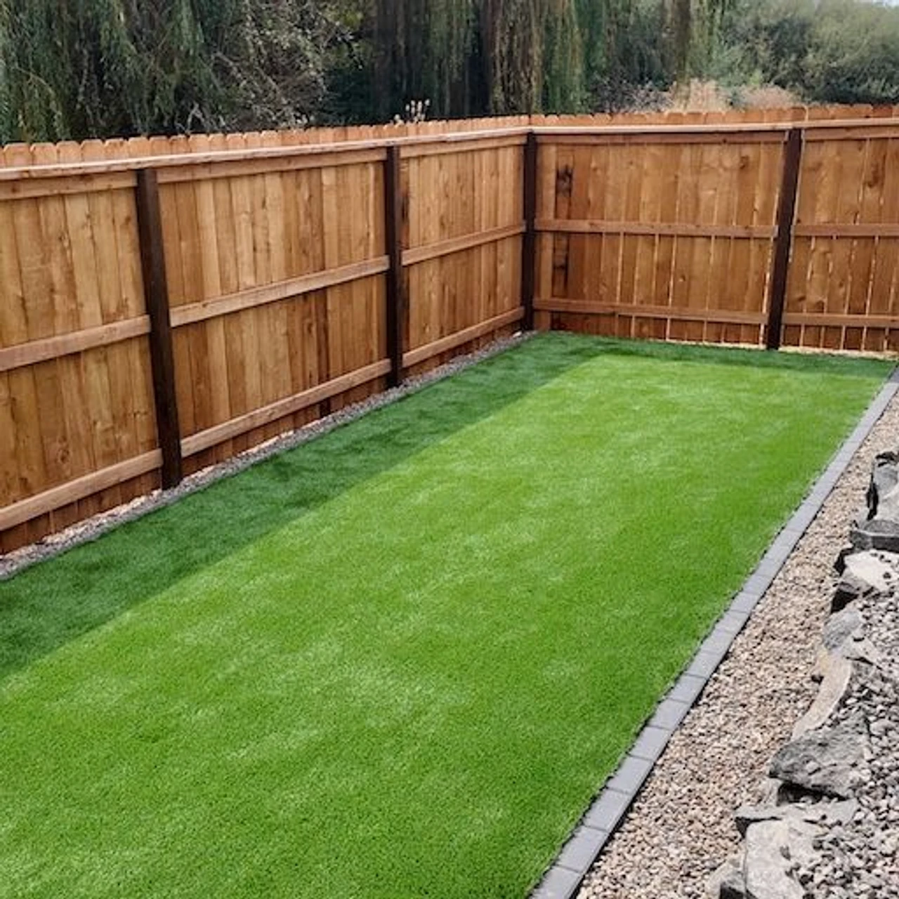 Rectangular turf installation with a wooden fence in the background