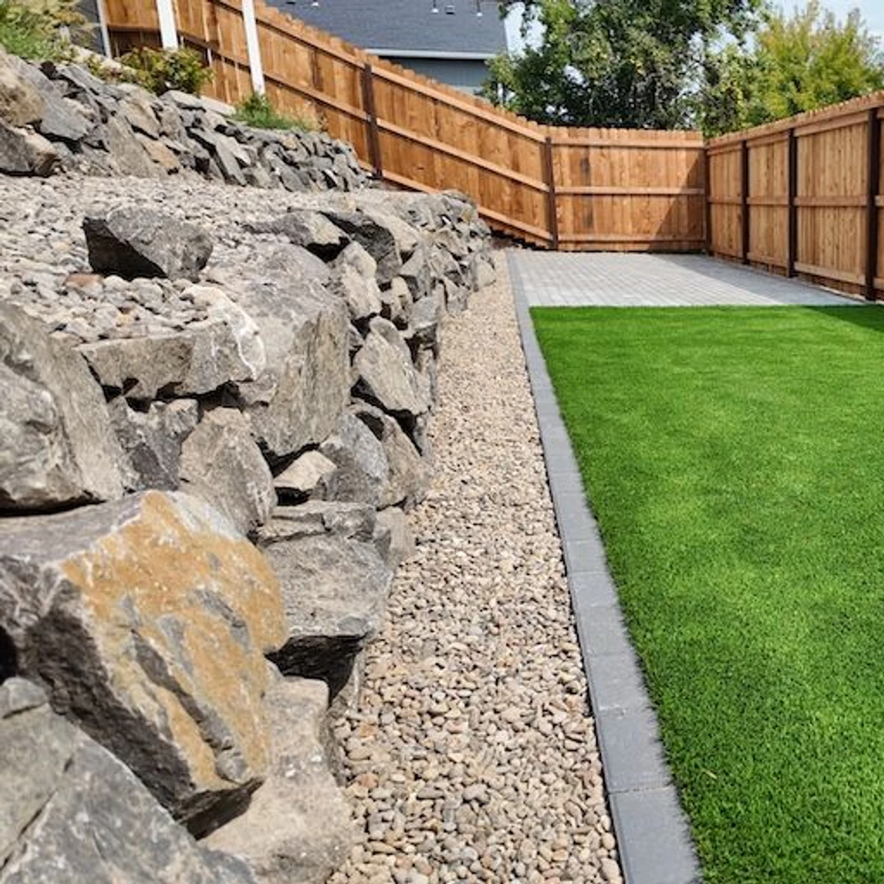Rectangular turf lawn with a rock retaining wall to the left