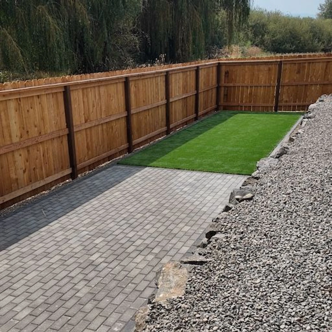 Bright green turf with pavers and. a retaining wall 